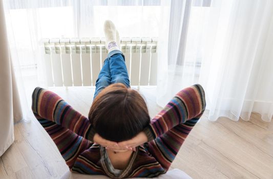 Woman laying on floor with feet raised up on radiator for warming