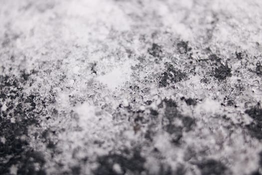 White snowflakes on a black surface macro photo