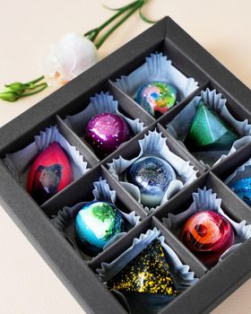 Black Gift box of handmade chocolates. Geometric and space design. Box on a light background. Sweets and candies close-up