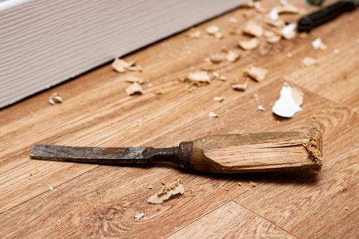 Chisel among sawdust on a wooden floor close up