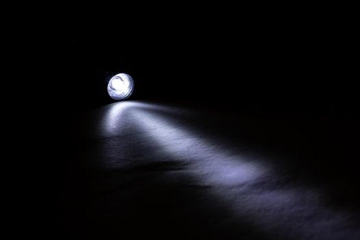 Blue light of a flashlight in the dark close up