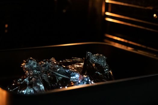Oven in foil in a baking sheet in dark
