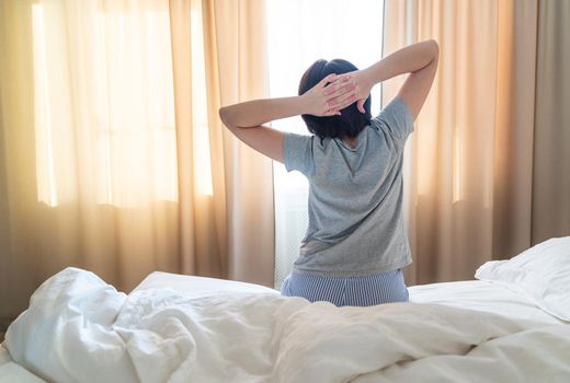 Woman stretching in bed after wake up, back view
