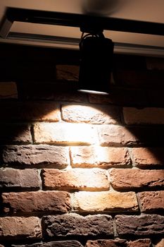 One bright lamp on a red brick wall indoor close up