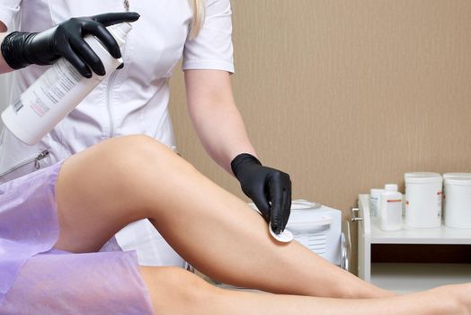 Beautician getting ready to wax female legs in spa center