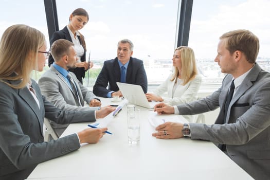 Mixed group of white collar workers at business meeting discuss documents