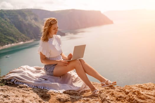 Freelance woman working on a laptop by the sea, typing away on the keyboard while enjoying the beautiful view, highlighting the idea of remote work