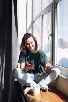 Connected and Productive: Woman Engaged in Smartphone Communication at Home - Student Balancing Work, Study, and Lifestyle through Mobile Apps and Technology.