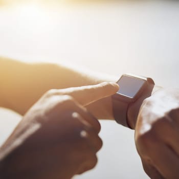 Workout the smart way. Closeup shot of an unrecognizable man checking his smartwatch while exercising outdoors