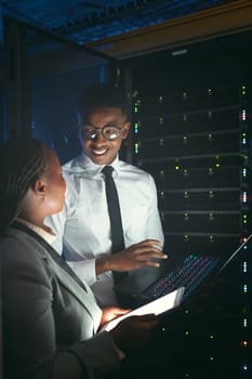 Sharing technical knowledge. two young IT specialists standing in the server room and having a discussion while using a technology