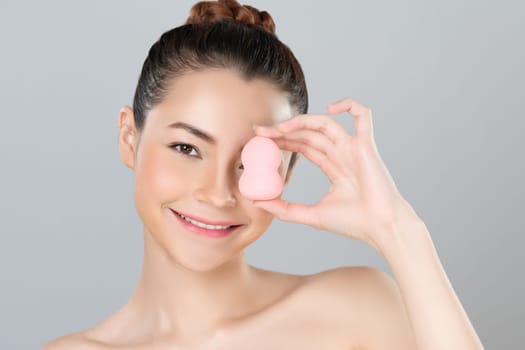 Glamorous beautiful female model applying cushion powder for facial makeup concept. Portrait of flawless perfect cosmetic skin woman put powder puff on her face in isolated background.