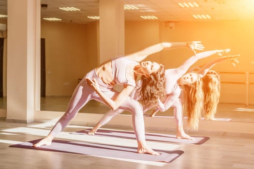 Young woman with long hair in white swimsuit and boho style braclets practicing outdoors on yoga mat by the sea on a sunset. Women's yoga fitness routine. Healthy lifestyle, harmony and meditation