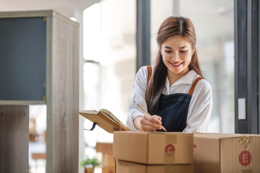 Startup small business entrepreneur SME, asian woman packing cloth in box. Portrait young Asian small business owner home office, online sell marketing delivery, SME e-commerce telemarketing concept...