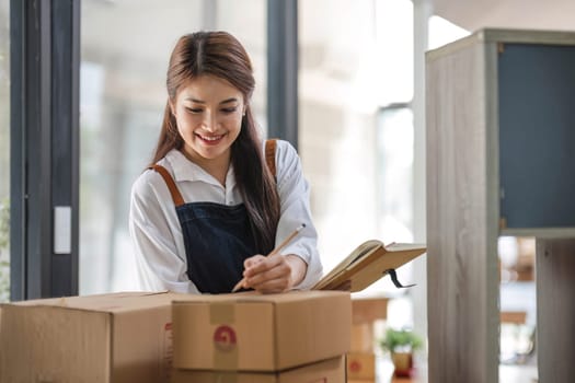 Startup small business entrepreneur SME, asian woman packing cloth in box. Portrait young Asian small business owner home office, online sell marketing delivery, SME e-commerce telemarketing concept...