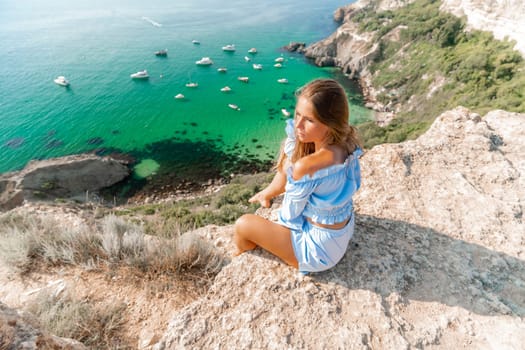 Woman travel sea. Happy woman in a beautiful location poses on a cliff high above the sea, with emerald waters and yachts in the background, while sharing her travel experiences.