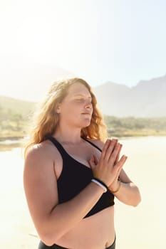 Yoga helps us to maintain a state of inner calm. a beautiful young woman practising yoga on the beach