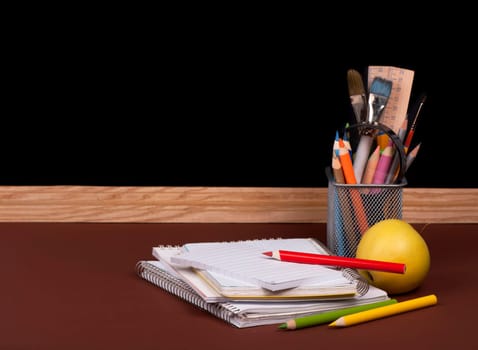 board, books, pencils, opened empty notebook against a dark background