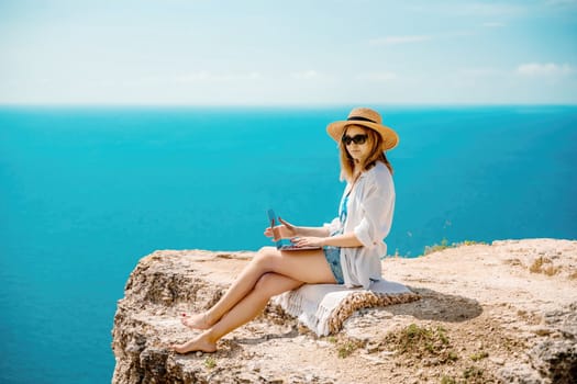 Freelance woman working on a laptop by the sea, typing away on the keyboard while enjoying the beautiful view, highlighting the idea of remote work