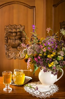 bouquet of wildflowers, honey and tea on the old board.