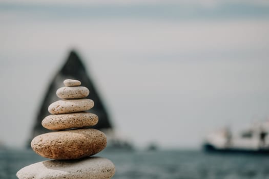 Pyramid stones on the seashore with warm sunset on the sea background. Happy holidays. Pebble beach, calm sea, travel destination. Concept of happy vacation on the sea, meditation, spa, calmness.