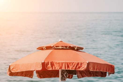 Red Beach Umbrella on the Background of the Blue Sea Ocean. Beach Landscape. Summer travel and holidays concept