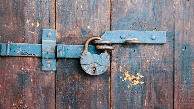 Rusty padlock on an old wooden door close up