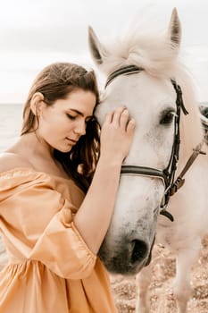 A white horse and a woman in a dress stand on a beach, with the sky and sea creating a picturesque backdrop for the scene