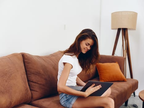 Woman freelancer sitting on the couch with a laptop beautiful smile , modern stylish interior Scandinavian lifestyle, copy space. High quality photo