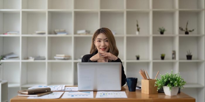 Happy young Asian business woman working at modern with a laptop.