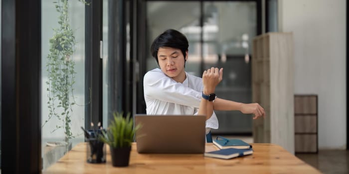 Stretching oneself asian business man with laptop in cafe. tried from work, stretch oneself.