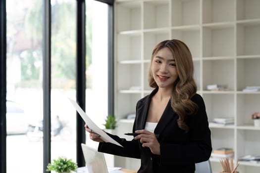 Happy young Asian business woman working at modern with a laptop.