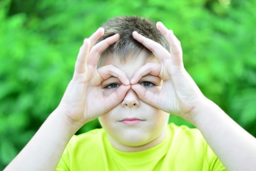 boy made glasses around his eyes with his fingers