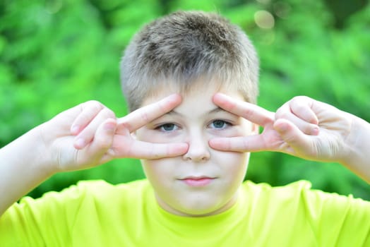 boy made glasses around his eyes with his fingers