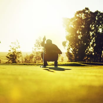 Every golf player is as good as his last putt. a young man eyeing up the putt during a round of golf