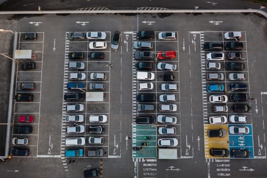 Aerial view of large parking lot in front shopping mall with many parked cars. Carpark at supermarket