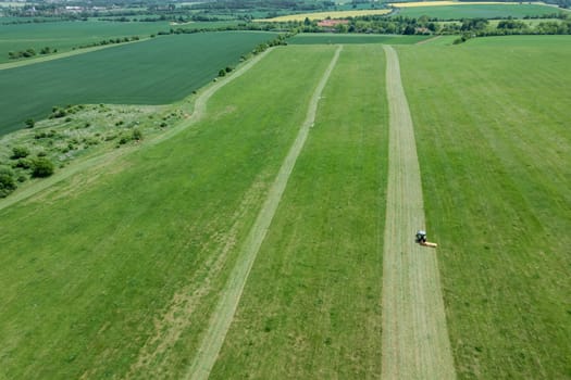 Top view of mowing grass on field. Grass is being efficiently trimmed by tractor's rotary cutting implement.