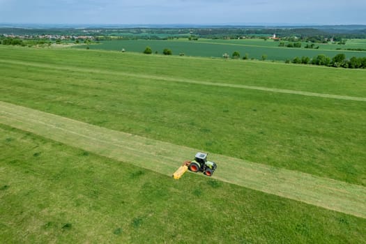 Field is being neatly mowed by the tractor's rotary cutter. Tractor mows the grass with a rotary mower.