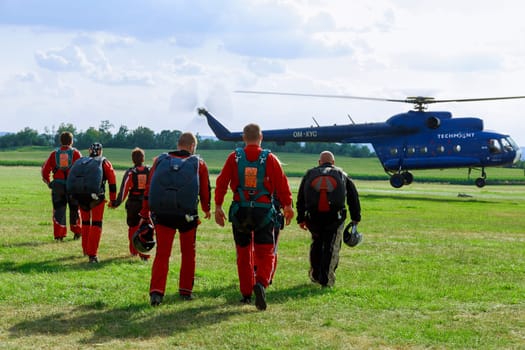 31 July 2022 Skutec, Czech Republic. Group of paratroopers go to helicopter for landing. Flight of paratroopers. Green field for landing paratroopers. Sports entertainment.