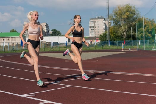 Two athlete young woman runnner on the start at the stadium outdoors