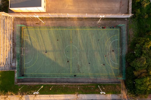 Aerial view of sport court in public park. Used to practice football. Top view. Sunny day. Sunset. Drone photo.