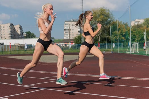 Two athlete young woman runnner on the start at the stadium outdoors