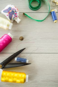 a set of tools and threads for sewing clothes, on a wooden background.