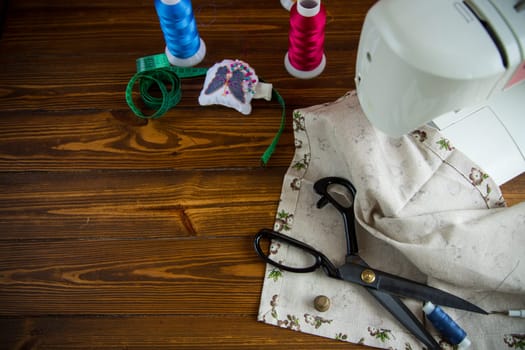 a set of tools and threads for sewing clothes, on a wooden background.