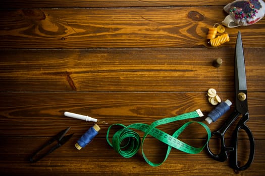 a set of tools and threads for sewing clothes, on a wooden background.