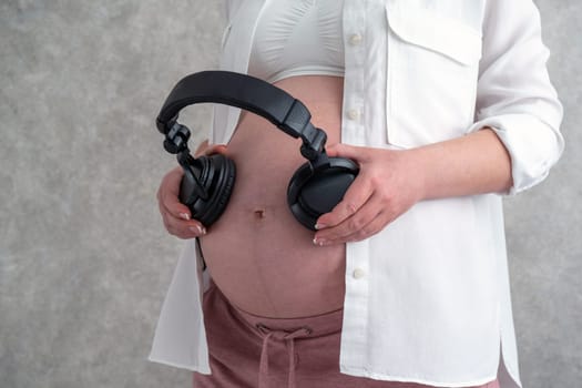 Pregnant woman putting headphones on her belly