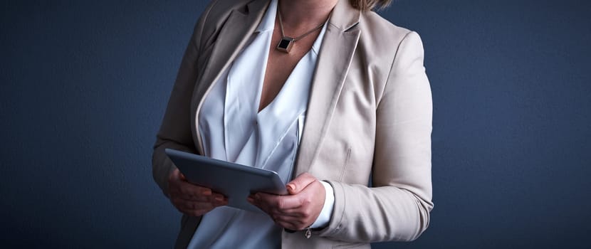 Every businessperson should own one. Studio shot of an unrecognizable corporate businesswoman using a tablet against a dark background