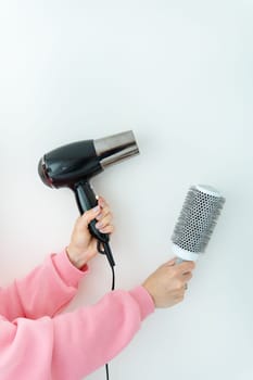 A girl holding a modern rotating head of a hair brush and a hair dryer in her hand. The concept of hair care in the salon