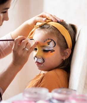 childrens makeup face paint drawings Girls face painting. Little girl having face painted on birthday party. closed eyes. kids birthday party. High quality photo