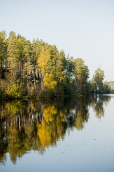 Autumn lake on dark background. Cloudy sky over autumn lake