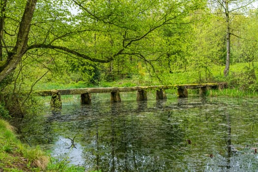 Old stone slab granite bridge across a pond or calm lake in English park land